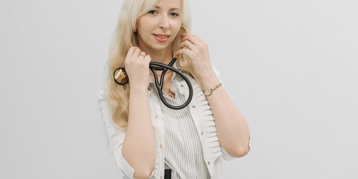 Confident female doctor posing with her stethoscope in a white coat indoors.